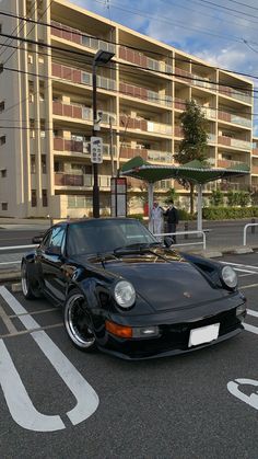 a black sports car parked in front of an apartment building