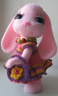 a crocheted pink bunny holding a purse