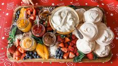 a platter filled with fruit and dips on top of a red table cloth