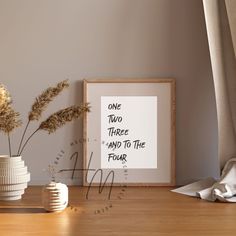 there are two vases with plants in them on the table next to a framed poster