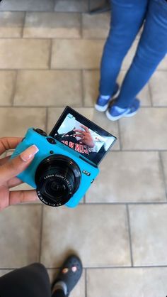 a person holding a camera in their hand on the ground with another person standing next to them