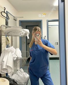 a woman in scrubs taking a selfie in front of a mirror with her cell phone