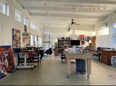 a room filled with lots of clutter and art work on the walls next to windows