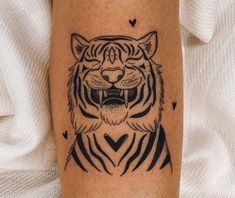 a black and white tiger tattoo on the right leg, with hearts in the background