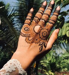 a woman's hand with henna on it and palm trees in the background