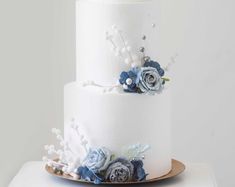 a three tiered white cake with blue flowers on top