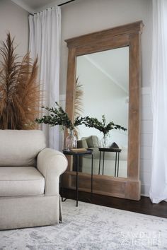 a mirror sitting on top of a table next to a white couch in a living room