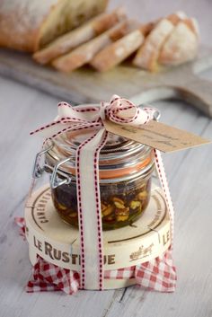 a glass jar filled with food sitting on top of a wooden table next to bread