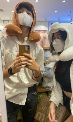 a man and woman wearing animal costumes taking a selfie in front of a mirror