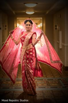 a woman in a red and gold sari holding a pink netted shawl