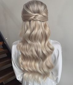 a woman with long blonde hair is standing in front of stairs