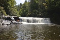 people are standing at the base of a waterfall