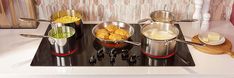 pots and pans sitting on top of a stove with food cooking in the middle