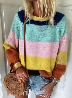 a blonde woman wearing a multicolored sweater and denim shorts holding a straw bag