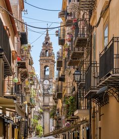 a narrow city street lined with tall buildings and balconies on either side of it