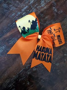 an orange ribbon with the words haruna matata on it is laying on a wooden surface