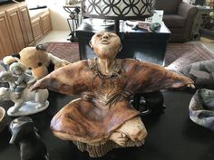 a wooden statue sitting on top of a table next to other figurines