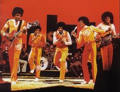 the jacksons performing on stage in front of a large group of people with guitars