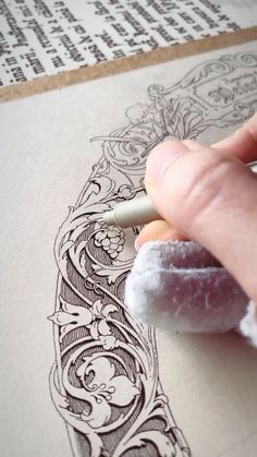 a person is drawing on paper with a pen and inking it onto some type of paper