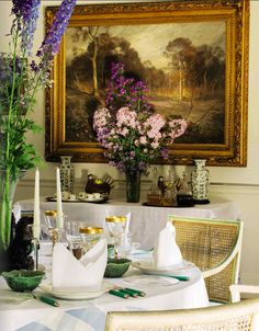 a dining room table set for two with flowers in vases