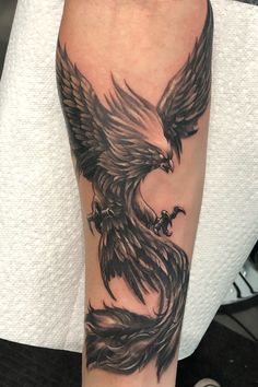 a man's arm with a black and grey eagle tattoo on his left leg