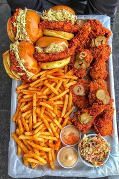 a tray filled with fried chicken, french fries and other food on top of it