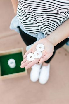 a woman is holding three white rings in her hands and sitting on the ground next to a box