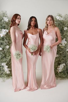 three bridesmaids in pink gowns posing for the camera with their bouquets