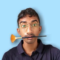 a man with glasses holding a paintbrush in front of his face to the side