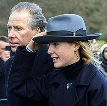 an older man and young woman wearing hats in front of a large group of people