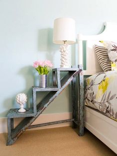 a white bed sitting next to a lamp on top of a table