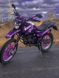 a purple dirt bike parked on top of a road