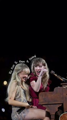 two women sitting next to each other on top of a piano