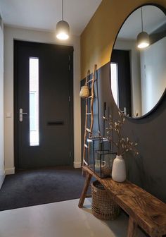 a wooden bench sitting in front of a mirror next to a wall mounted light fixture