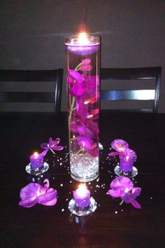 a vase filled with purple flowers sitting on top of a wooden table next to candles