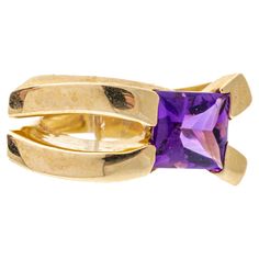 14k yellow gold ring. This unusual ring has a square, half-faceted, and half cabochon cut, medium to dark purple color amethyst, offset into a wide, elongated contemporary split, decorated with broad, split shoulders. Marks: 14k Dimensions: 15/16" across the top x 5/16" wide Weight: 6.8 gross dwt Ring Size: 8.25 Yellow Gold Amethyst Ring, Amethyst Cocktail Ring, Dark Purple Color, Gold Amethyst Ring, Amethyst Set, Unusual Rings, Amethyst And Diamond Ring, Rainbow Rings, Gold Cocktail Ring