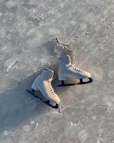 two white ice skates sitting on top of an ice covered surface with strings attached to them