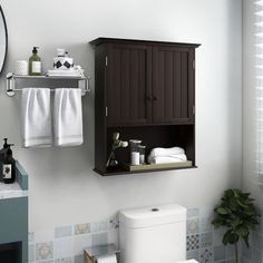 a white toilet sitting next to a wooden cabinet in a bathroom under a mirror and towel rack