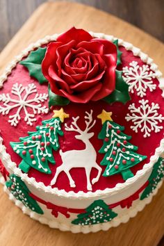 a decorated christmas cake with a red rose and green decorations on it's side