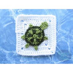 a crocheted square with a green turtle on it's side in the water