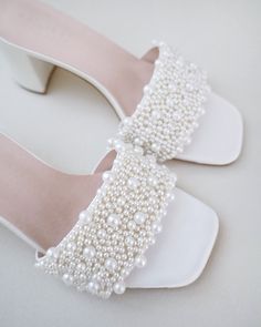 a pair of white shoes with pearls on them