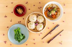 three bowls filled with food next to chopsticks and other items on a table