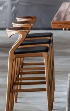 several wooden chairs sitting next to each other on top of a cement floor in front of a table