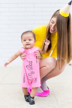 a woman holding a baby wearing a pink onesie