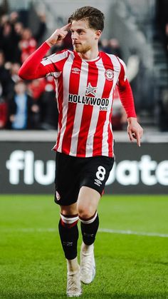 a soccer player is running on the field with his hand up to his ear and head