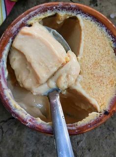 a spoon in a bowl filled with ice cream and some kind of sauce on top of it