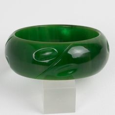 This is part of Chairish’s Costume Jewelry assortment.  This is a stunning basil green marble Bakelite carved bracelet bangle. It features a chunky domed shape with a geometric carving design all around. The color is an intense green marble tone with cloudy swirling.  Measurements: Inside across 2.63 in diameter (6.6 cm) - outside across 3.25 in diameter (8.2 cm) - width is 1.13 in wide (2.9 cm) - The inner circumference of the bracelet is 8.16 in (20.72 cm).  Please see the measurements noted a Elegant Carved Green Bangle, Green Carved Bangle Bracelets, Green Carved Bangle Bracelet, Elegant Green Carved Bangle, Carved Green Jade Bangle, Green Carved Round Bangle, Carving Designs, Green Marble, Bracelet Bangle