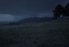 dark clouds hover over a grassy hill at night