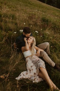 a man and woman laying in the grass with their heads touching each other's noses