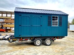 a blue trailer with a small cabin on the back